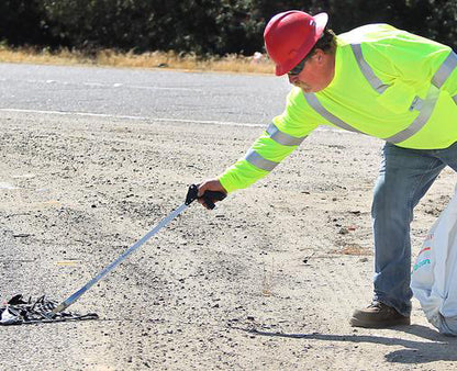 man in safety gear picking up trash with EZ Reacher